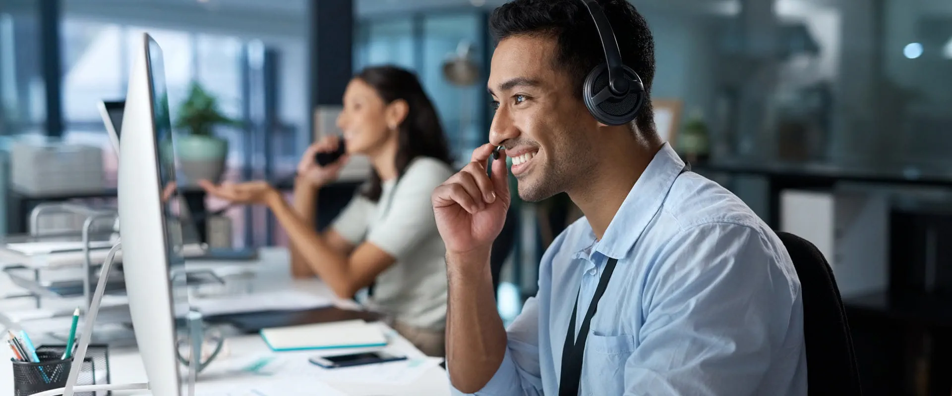 Smiling person using a headset and computer in a modern office.