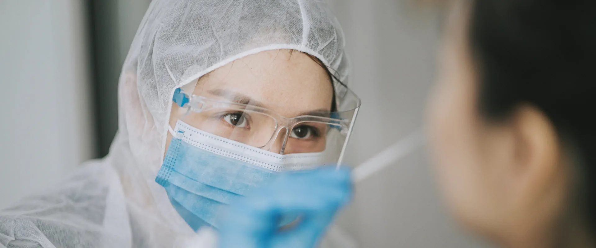 Doctor wearing PPE taking swab from patient.