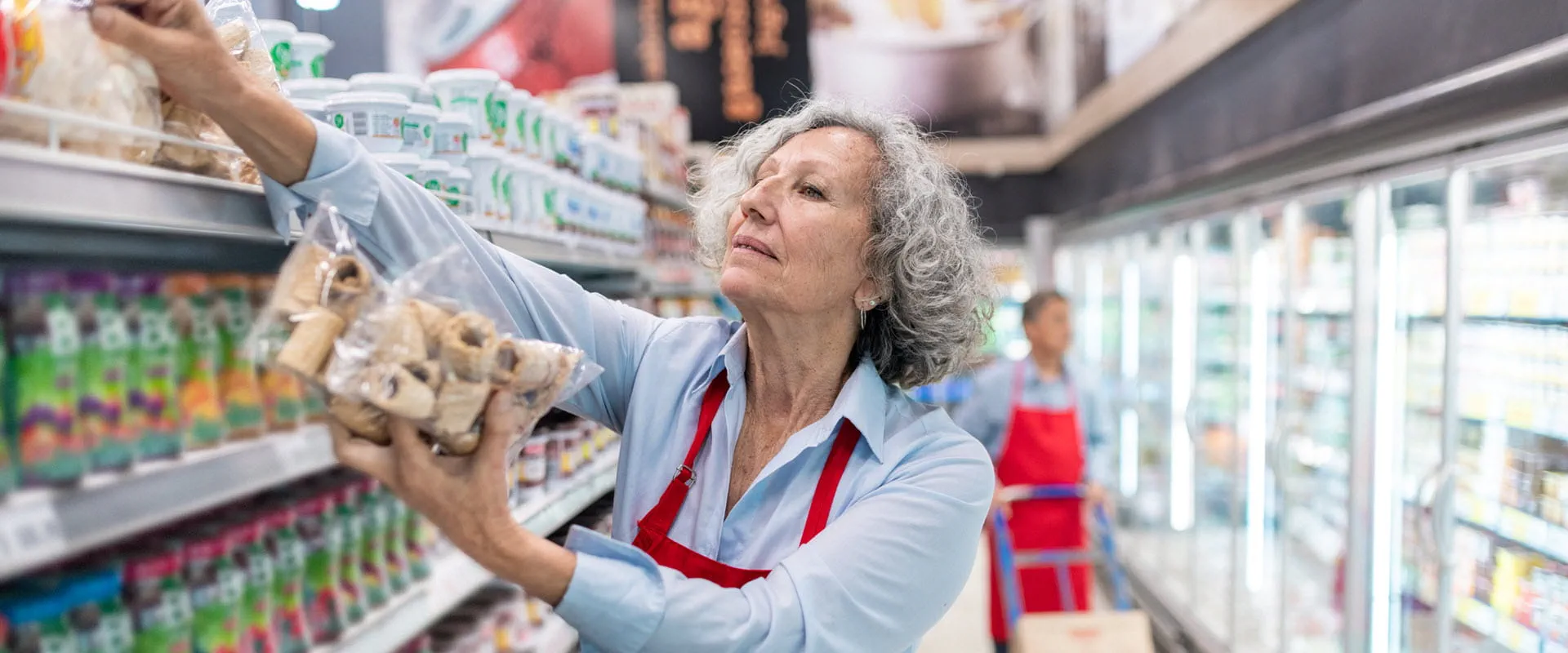 A senior worker stocking shelves in a grocery store.