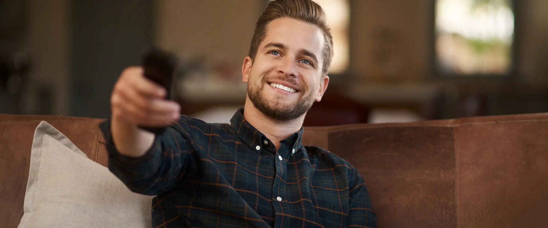 smiling man on couch with remote control