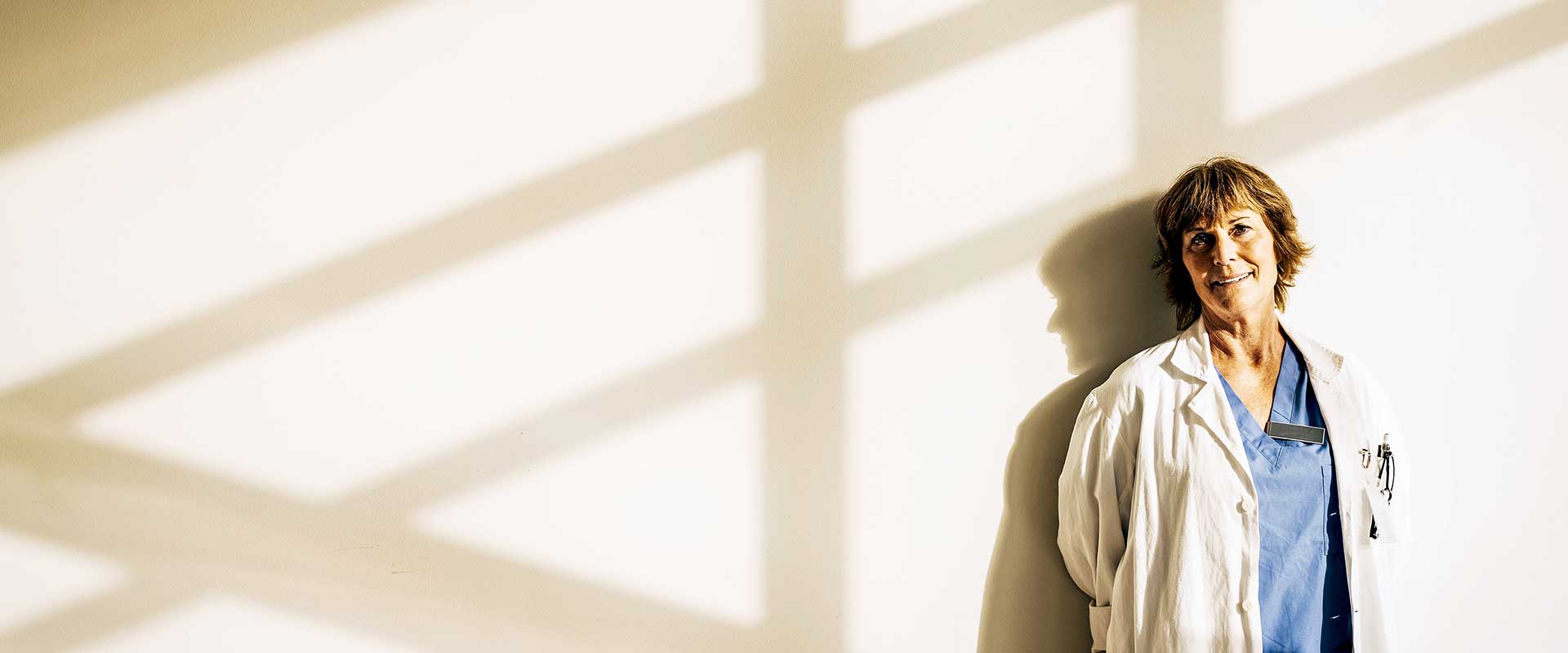 Doctor standing in natural light in hospital corridor Doctor standing in natural light in hospital corridor