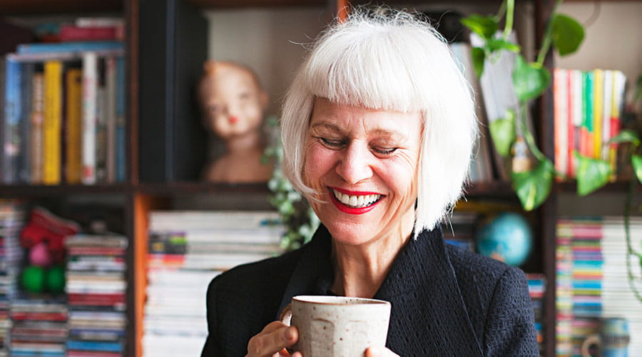  Elderly woman smiling while holding cup in cosy setting