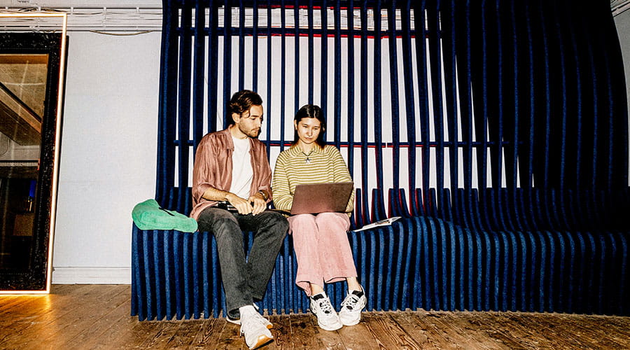  Two people sitting with laptops in modern workspace
