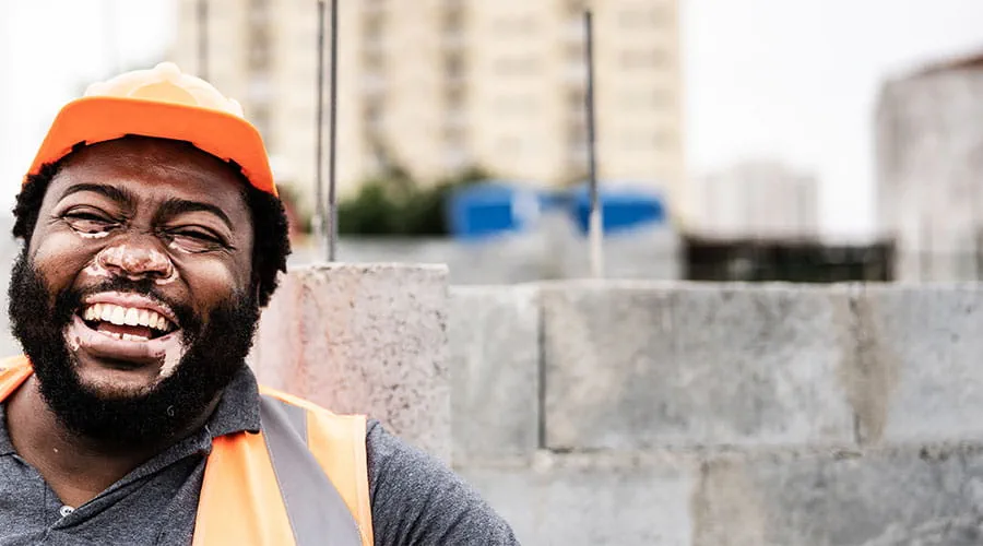 Operaio con dispositivi di sicurezza sorridente in un ambiente esterno Operaio con dispositivi di sicurezza sorridente in un ambiente esterno