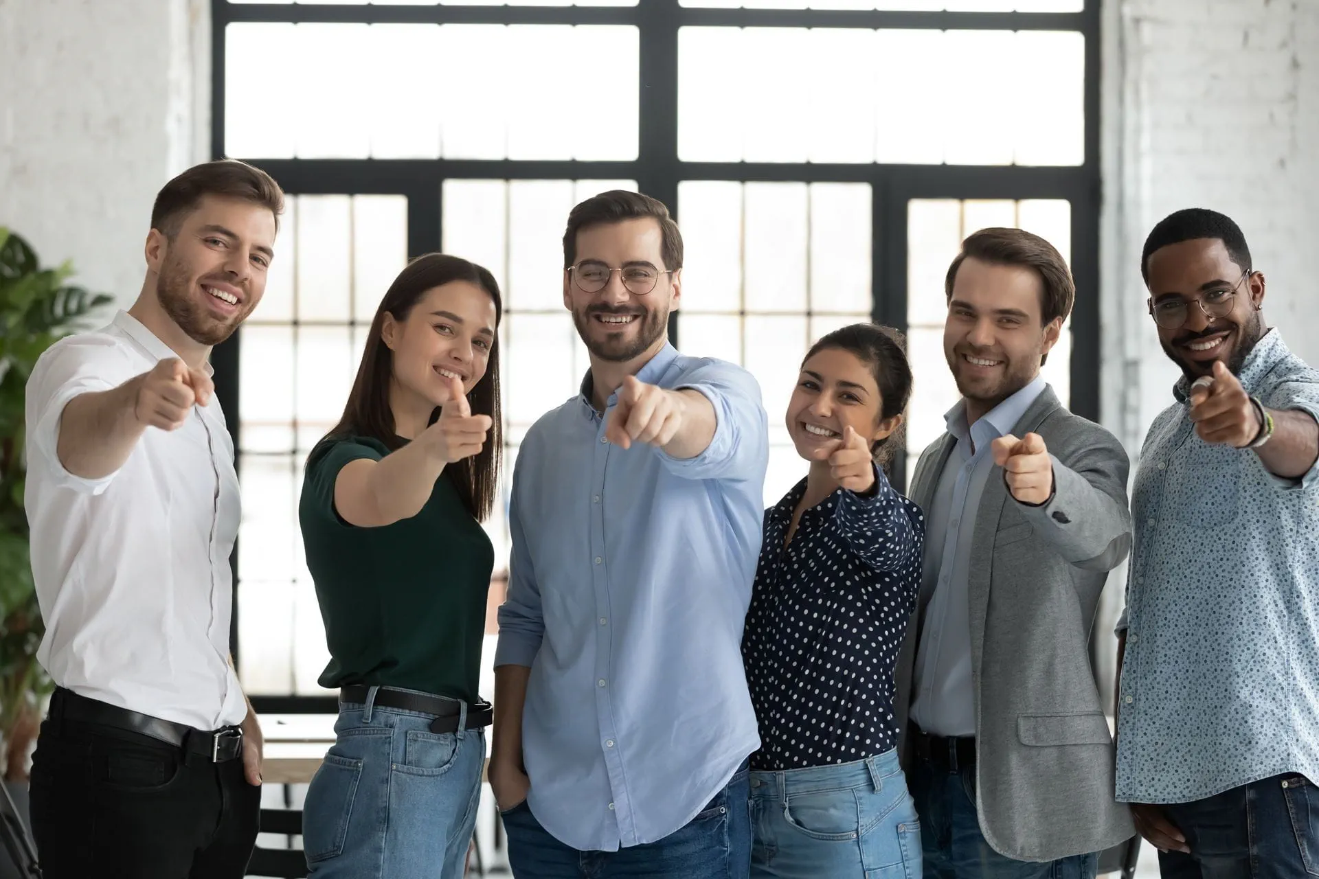 Smilende kollegaer i et mangfoldig og  positivt team i et moderne kontormiljø.  Profesjonell og vennlig utstråling.